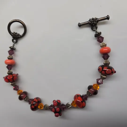 A handcrafted red and amber lampwork glass bead bracelet with a toggle clasp